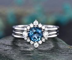 a blue and white diamond ring sitting on top of a rock