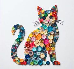 a cat made out of buttons sitting on top of a white table next to a wall