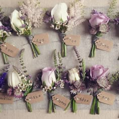 wedding bouquets with name tags are arranged on a linen tablecloth for seating cards