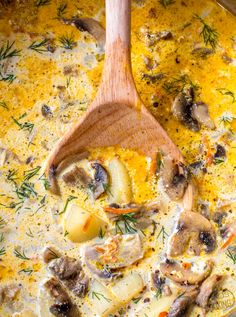 a wooden spoon in a pot filled with mushroom and cheese soup on top of a table