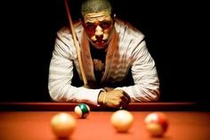 a man leaning over a pool table with cues in front of him and balls on the ground