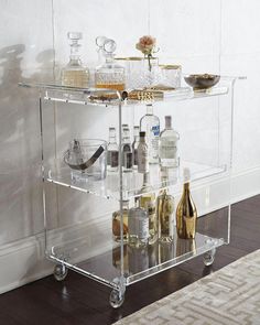 a clear bar cart with bottles and glasses on it