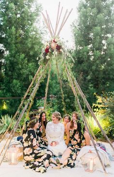 a group of women sitting in front of a teepeet with candles on it