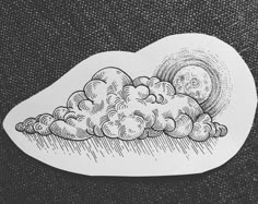 a drawing of clouds and the moon on a black background with white paper over it