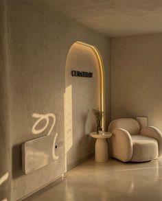 a room with a chair, table and lamp on the wall in front of it