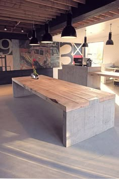 a wooden bench sitting in the middle of a room with lights hanging from it's ceiling