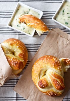 two hot dogs wrapped in bread on top of a table next to some dipping sauces