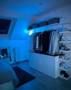 a bedroom with blue light coming from the ceiling and clothes hanging on shelves in it