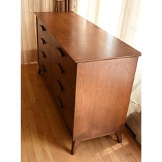 a large wooden dresser sitting on top of a hard wood floor next to a window