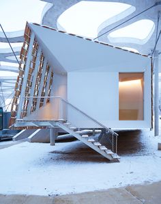 a white building with stairs leading up to it's entrance in the middle of snow