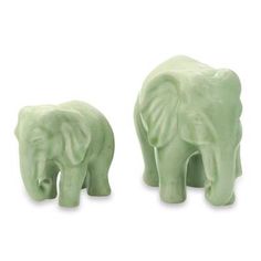 two green elephant figurines sitting next to each other on top of a white surface