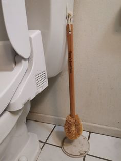 a toilet brush sitting on the floor next to a urinal