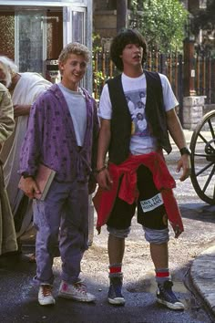 two men standing next to each other on the street