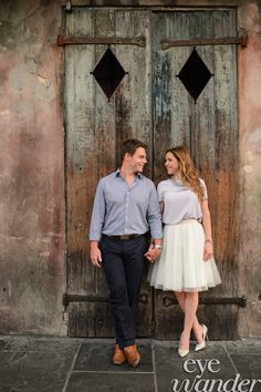 a man and woman standing next to each other in front of an old wooden door