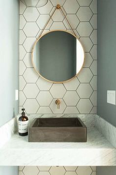 a bathroom with hexagonal tiles and a round mirror on the wall above it