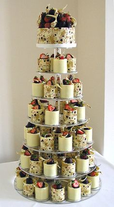 a tiered cake display with cupcakes and fruit on it's sides