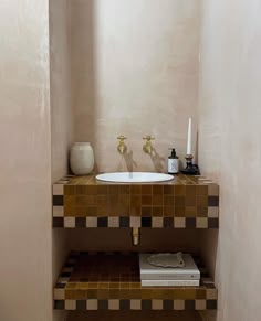 a bathroom sink sitting under a window next to a shelf with a book on it