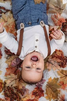 an overhead view of a baby laying on leaves