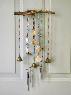 a wind chime hanging from a wall with shells and beads on it's sides