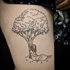 a woman sitting under a tree tattoo on her thigh