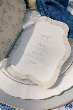 a table setting with blue and white plates, napkins and silverware on it