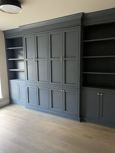 an empty living room with built - in bookcases and hard wood flooring