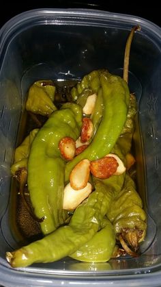 green peppers in a plastic container with nuts and other food items on the top of them