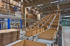 boxes are stacked up in a large warehouse with pallets on the conveyor belt