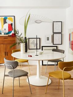 a white table with four chairs around it in a room filled with pictures and artwork