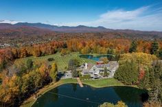 an aerial view of a large house surrounded by trees and mountains in the fall season