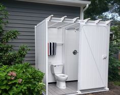 a white toilet sitting inside of a bathroom next to a garden shed with its door open