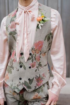 a man wearing a floral suit and pink bow tie with his hands in his pockets