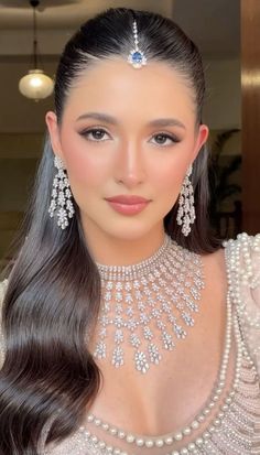 a woman with long hair wearing a necklace and earrings