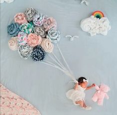 a baby girl holding onto a bunch of fabric flowers with a pink teddy bear next to it