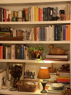 a bookshelf filled with lots of books next to a lamp and other items