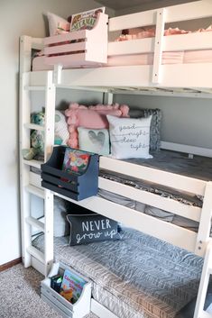 a white bunk bed sitting next to a book shelf filled with stuffed animals and books