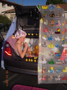 a man sitting in the back of a car with an open trunk filled with toys