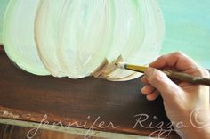 a person painting a white flower on a piece of wood