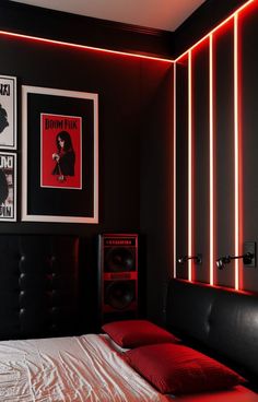 a bed in a bedroom with red lights on the wall and pictures above it,