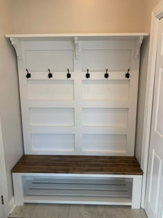 an empty white bench in the corner of a room with built - in shelving