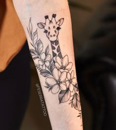 a giraffe with flowers and leaves on its arm is seen in this image