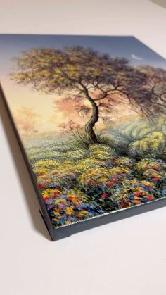 a painting on a white surface with a tree in the middle and flowers all around it