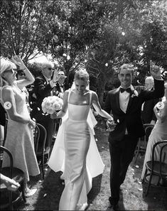 black and white photo of bride and groom walking down aisle with confetti thrown in the air