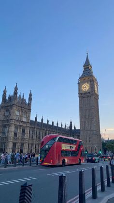 a red double decker bus driving past the big ben clock tower in london, england