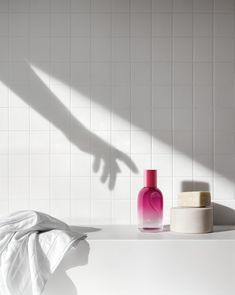 the shadow of a person's hand on a white tiled wall