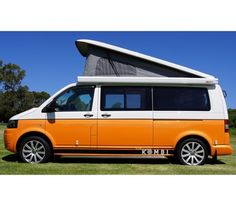 an orange and white van parked in the grass with a roof tent on it's top