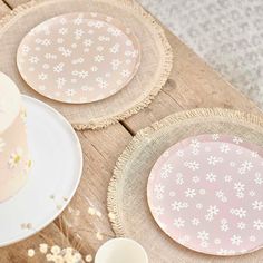 a table topped with pink and white plates next to a cake on top of a wooden table