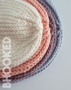 four different colored knitted hats sitting on top of each other