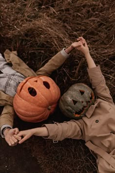 a young boy laying on the ground next to a pumpkin