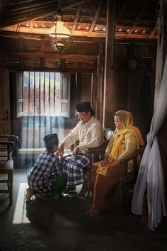 a man sitting in a chair next to two women and a young boy on the floor